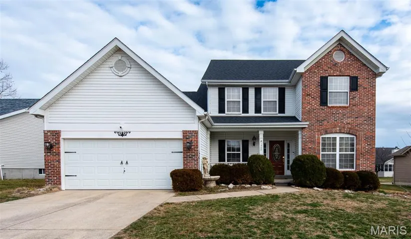 Traditional-style house with concrete driveway, a porch, brick siding, and a garage