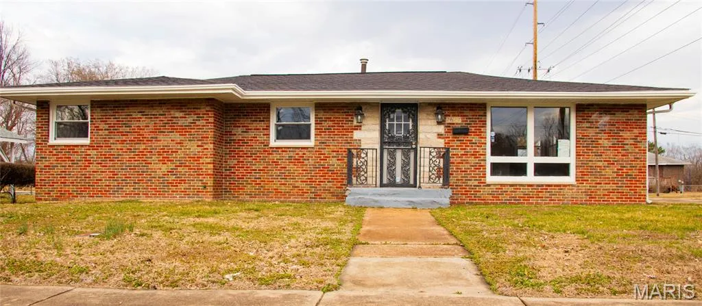 Single story home with a front lawn and brick siding
