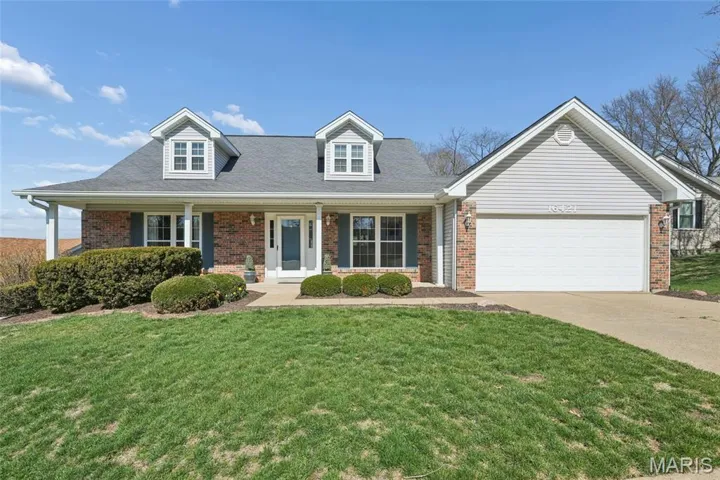 Cape cod house with brick siding, a front yard, a garage, a porch, and driveway