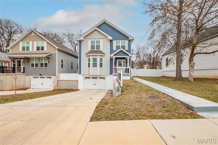 View of front of home with driveway, an attached garage, a front lawn, and covered porch