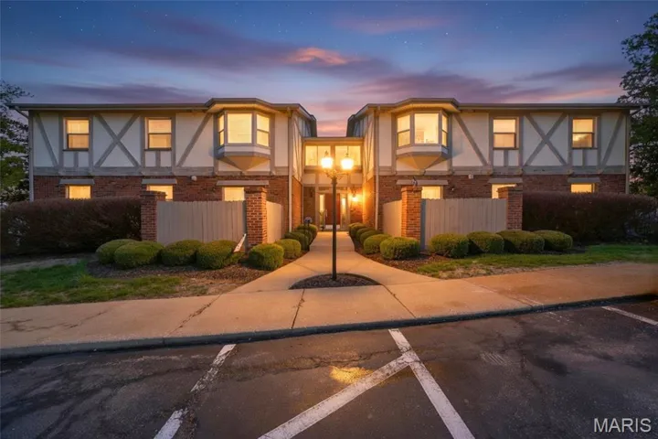 Tudor Condo with brick siding, stucco siding, and uncovered parking