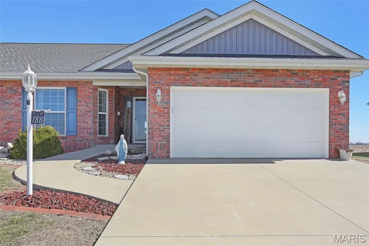 View of front facade featuring brick siding, driveway, an attached garage, and a shingled roof