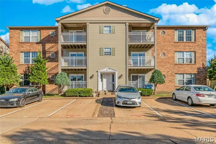 View of apartment building / complex featuring uncovered parking