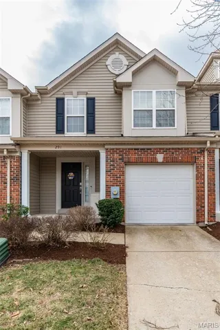 Traditional-style home with driveway, covered porch, attached garage, and brick decorative siding