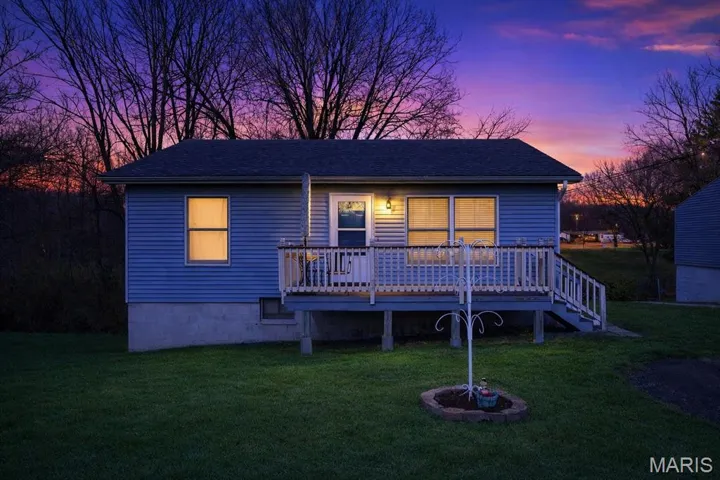 Front of house at dusk with a lawn and a deck