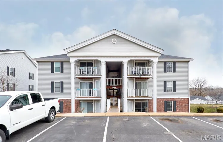 View of apartment building / complex featuring uncovered parking