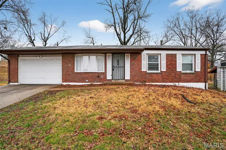 Single story home featuring an attached garage, driveway, brick siding, and a front yard