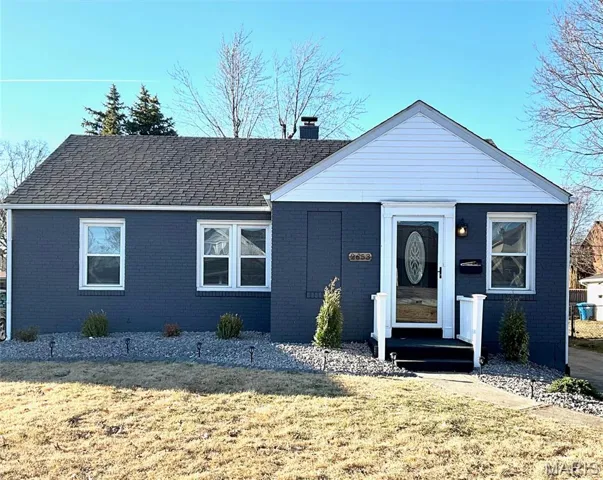 View of front of property featuring a front yard, a chimney, and brick siding