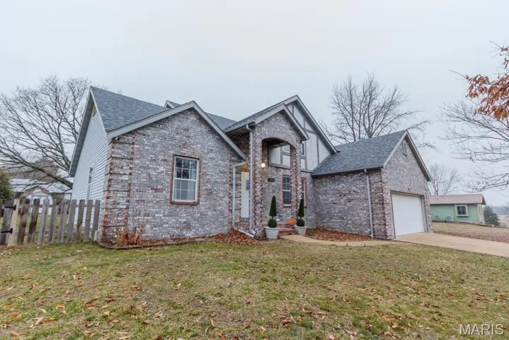 View of front of property with brick siding, driveway, and an attached garage
