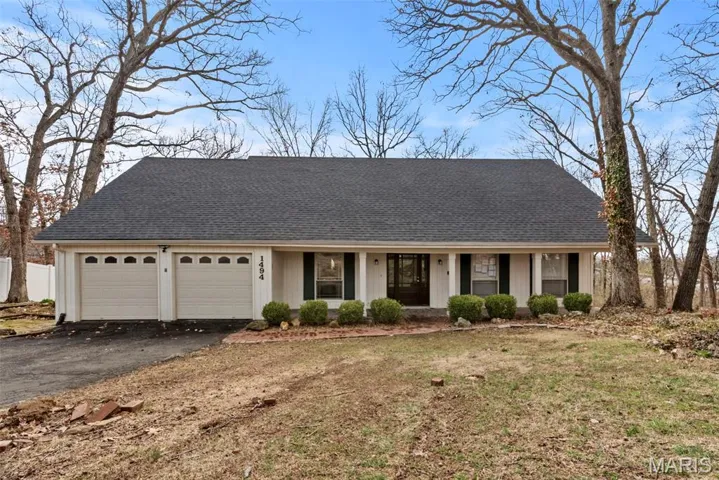 View of front facade with covered porch, an attached garage, asphalt driveway, a shingled roof, and a front yard