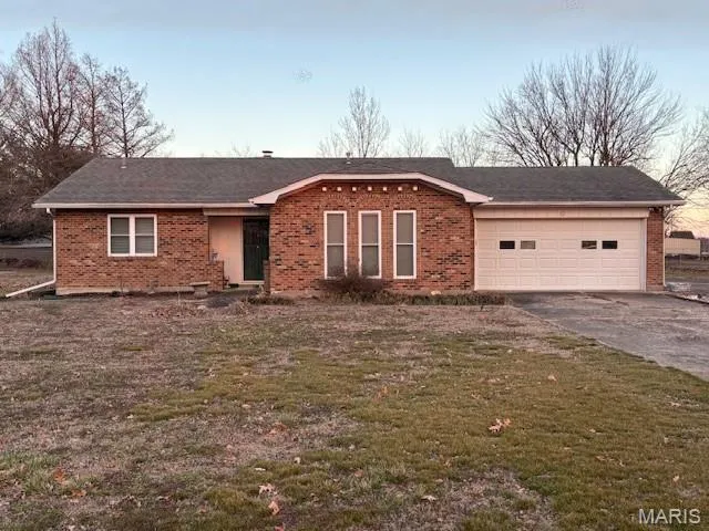 Single story home featuring brick siding, an attached garage, asphalt driveway, and a front lawn