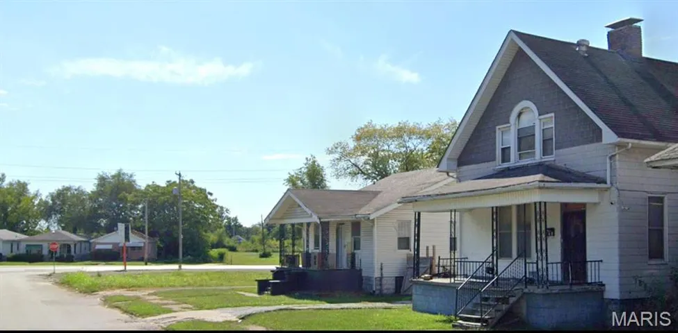 View of side of home with a porch and a yard