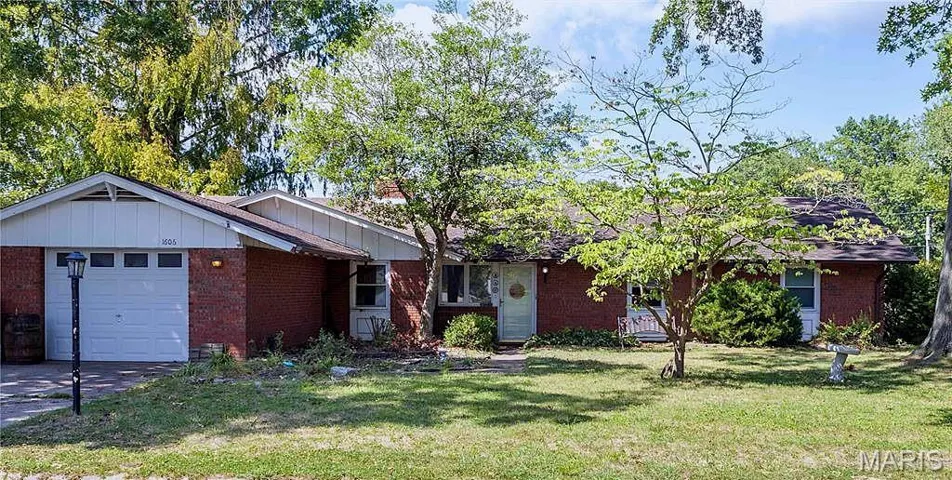 Ranch-style house featuring brick siding, a garage, board and batten siding, a front yard, and driveway