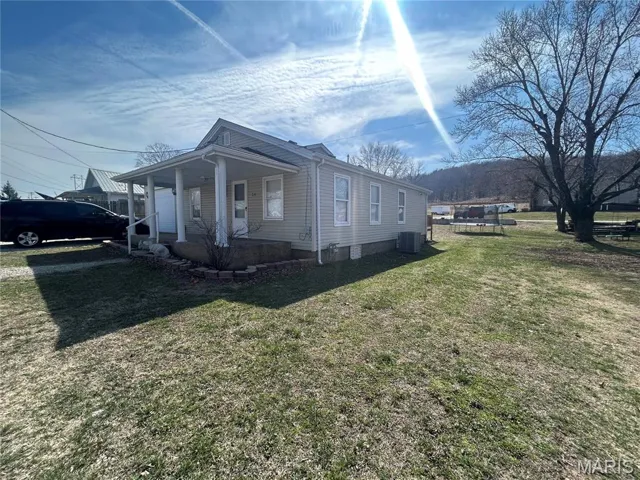 View of side of property with a porch and a lawn