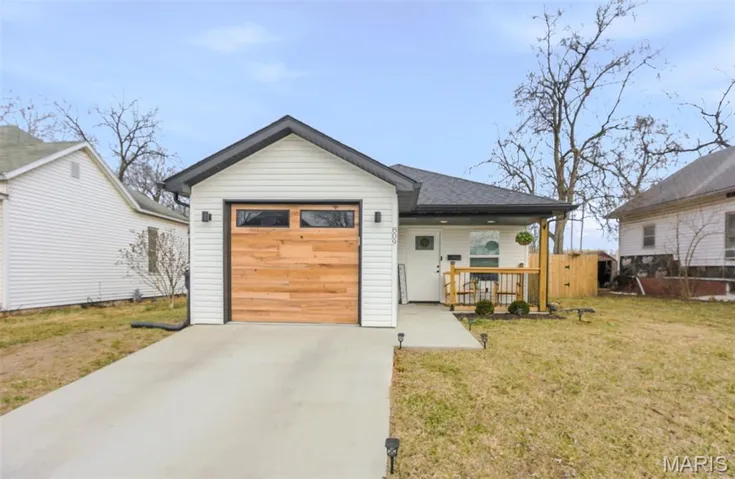 View of front of home featuring driveway, a front yard, covered porch, and an attached garage