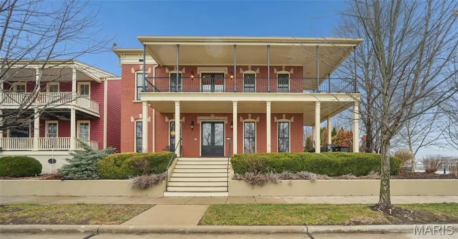 View of front of house featuring brick, covered porch, and a balcony