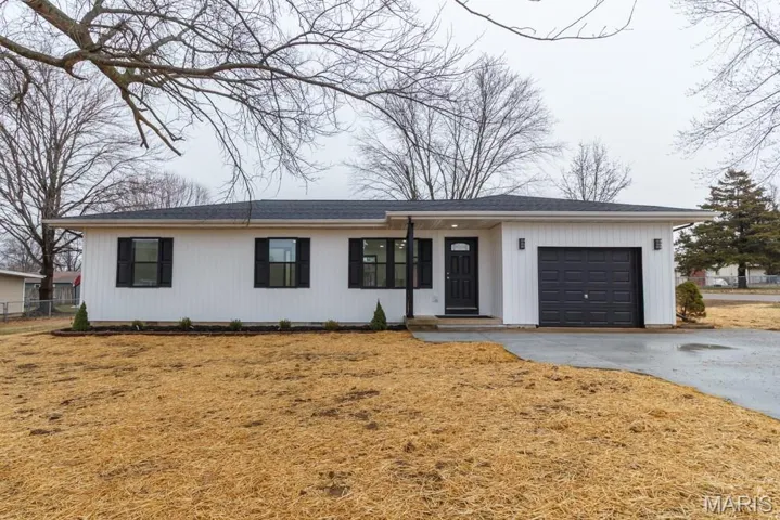 View of front of house featuring an attached garage, asphalt driveway, and roof with shingles
