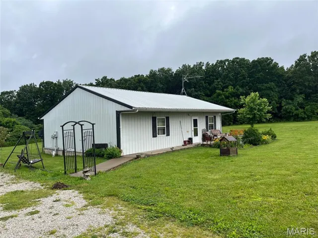 View of front of home with a front lawn, a metal roof, and an outbuilding