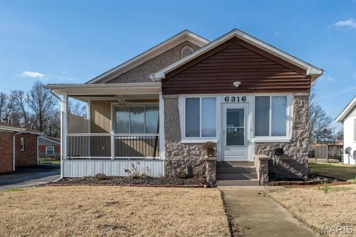Front view of home featuring a front yard, a sunroom and covered porch