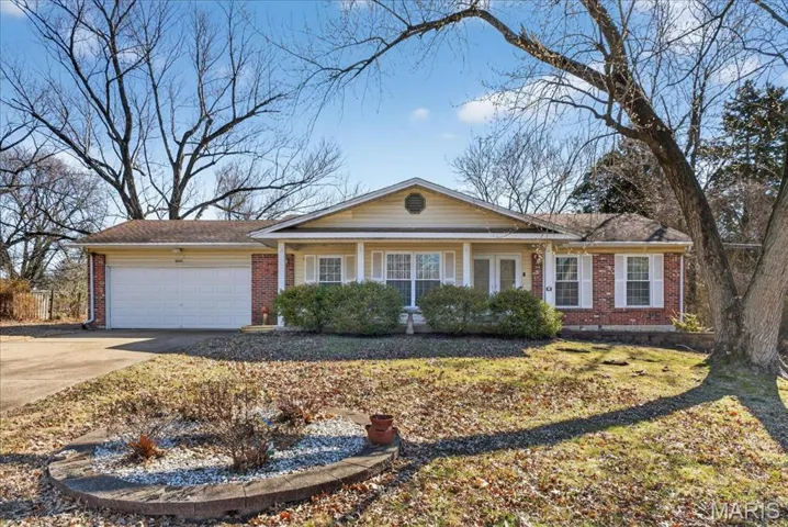 Ranch-style home with covered porch, a garage, concrete driveway, and brick siding
