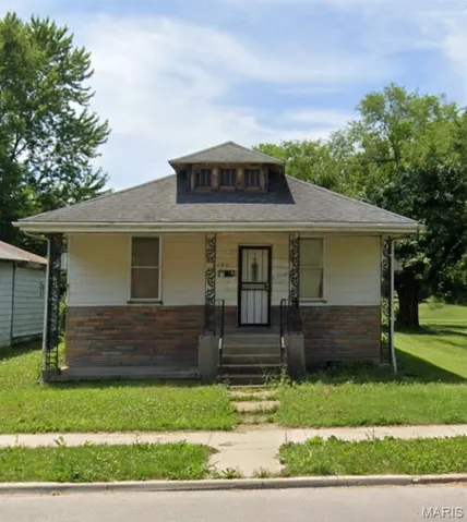 Bungalow with a porch, a front yard, and brick siding