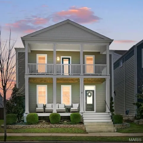 Stunning twilight view of this elegant New Town residence, where classic architecture, double front porches, and warm interior glow create a breathtaking first impression