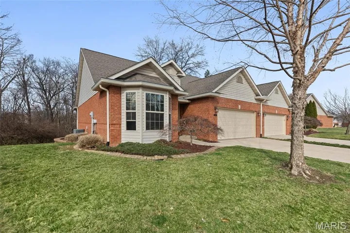 View of front of property with brick siding, driveway, an attached garage, and a front yard