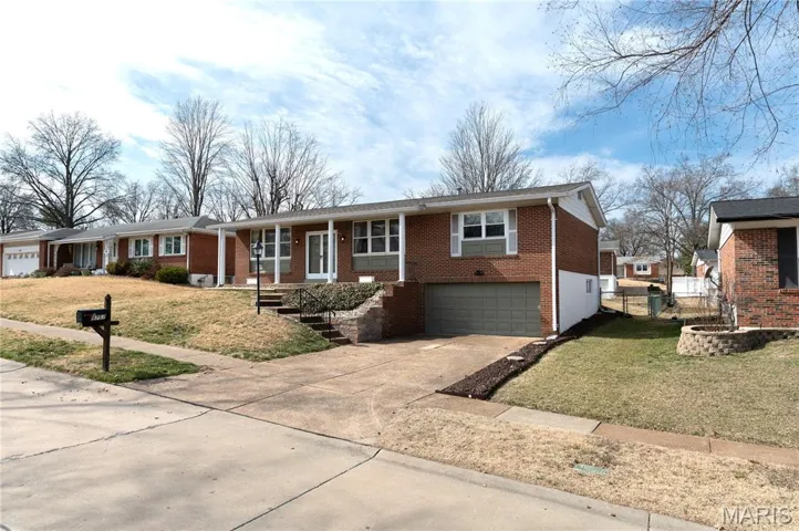 Single story home with concrete driveway, an attached garage, and brick siding