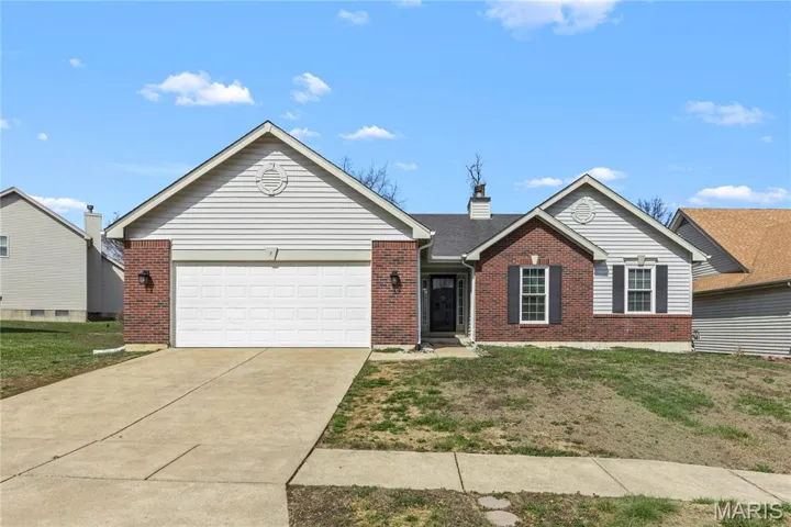 Ranch-style home featuring a front lawn, an attached garage, concrete driveway, and brick siding