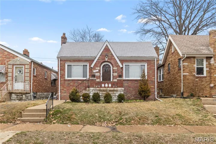 Tudor home featuring brick siding, a front yard, roof with shingles, and a chimney
