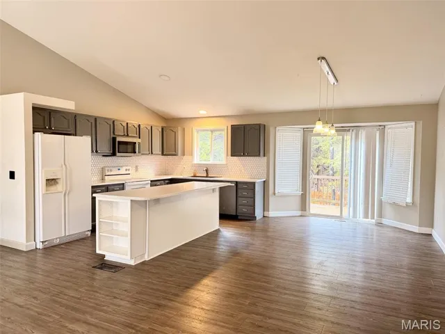Kitchen featuring stainless steel appliances, a center island, lofted ceiling, backsplash, and pendant lighting