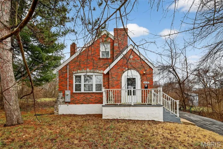 View of front facade featuring brick siding and a chimney