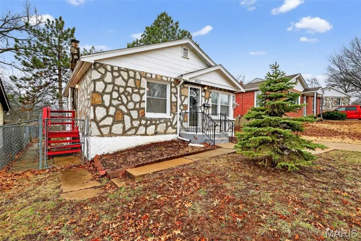 View of front facade featuring a chimney and stone siding