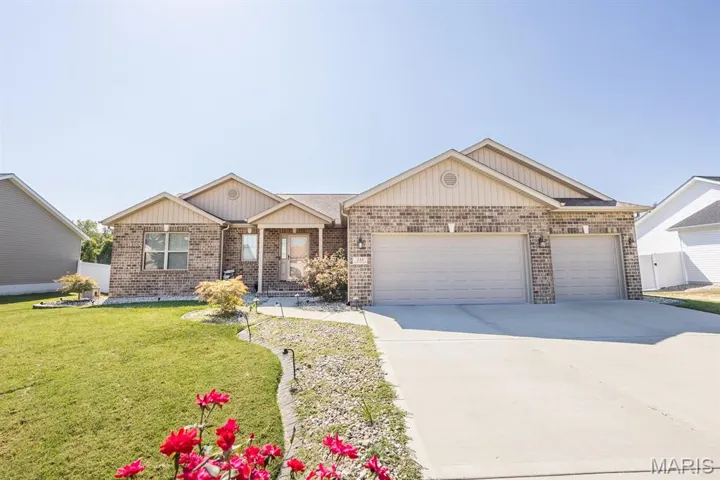 Ranch-style house with brick siding, driveway, an attached garage, and a front lawn