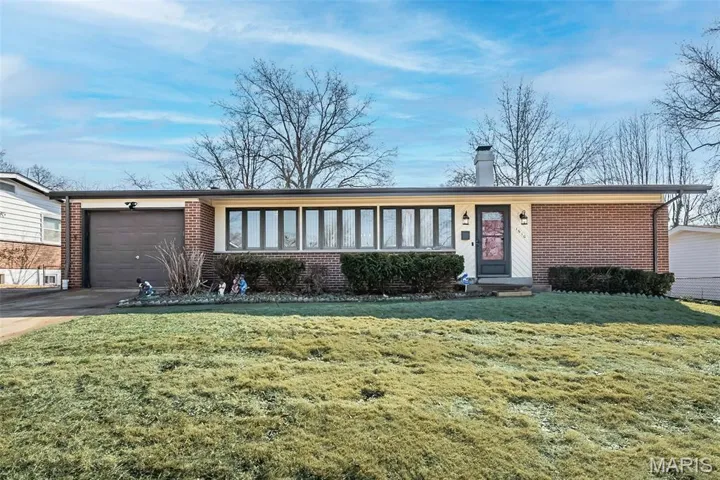 Ranch-style home with brick siding, a garage, a chimney, driveway, and a front yard
