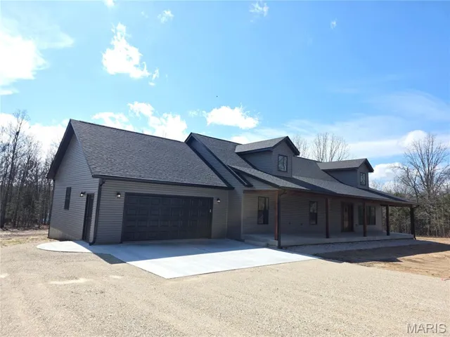 View of front home featuring concrete driveway, a shingled roof, a garage, and large covered porch!