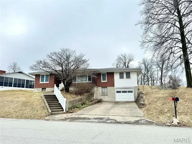 Ranch-style house featuring a garage, driveway, and brick siding