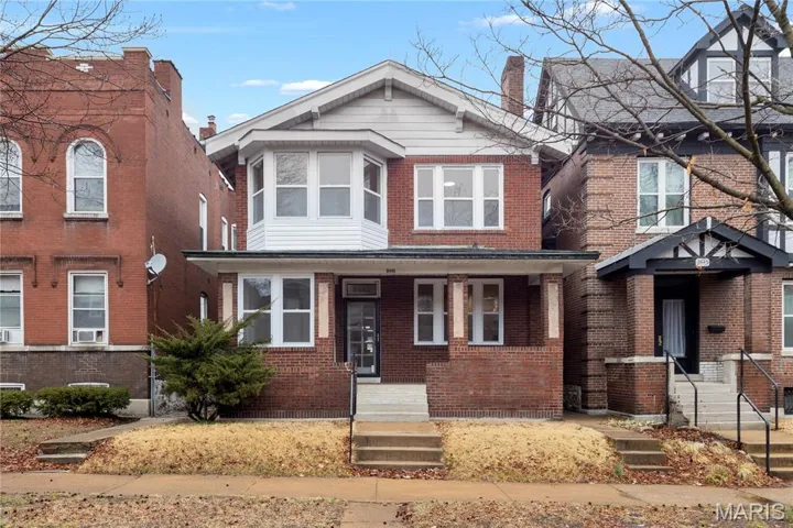 View of front of house featuring brick siding and a chimney