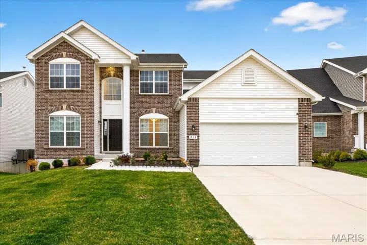 View of front facade featuring brick siding, driveway, and a front yard