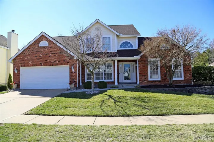 Traditional-style house with driveway, a front lawn, and brick siding