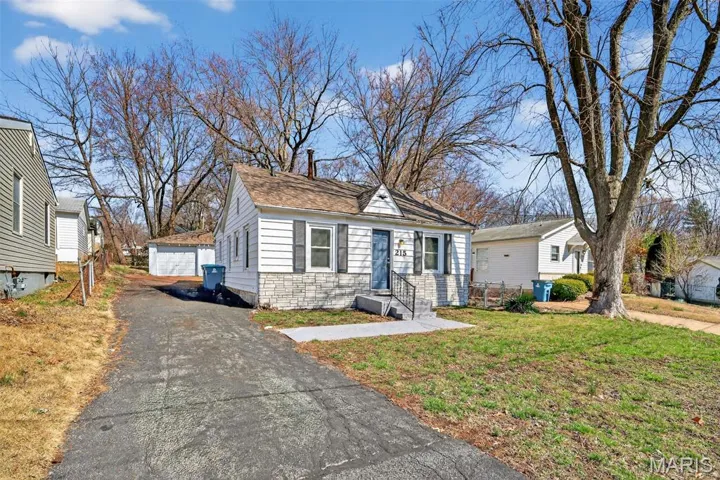 View of front of house featuring an outdoor structure, a front yard, and a detached garage
