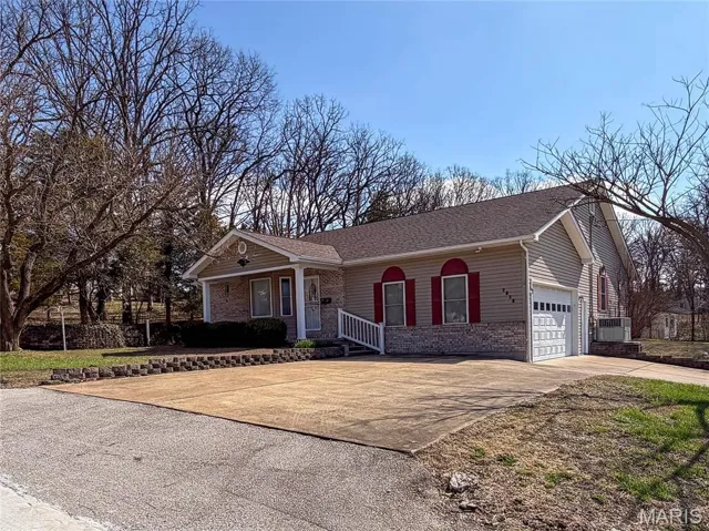 Ranch-style home featuring concrete driveway, brick and vinyl siding, a porch, and attached garage
