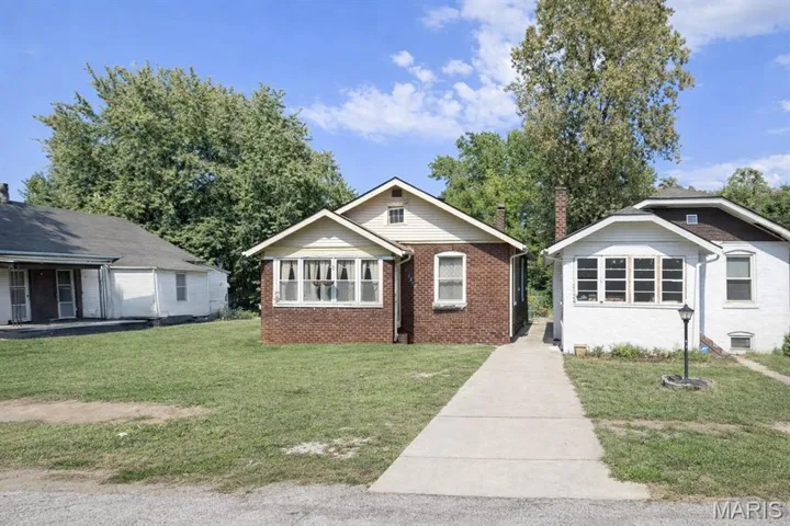 Bungalow-style house with brick siding, a front yard, and a chimney