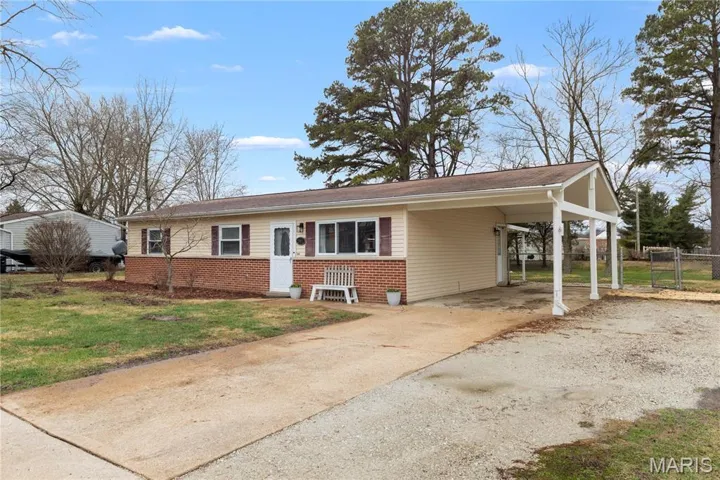View of front of house with driveway, brick siding, and a carport