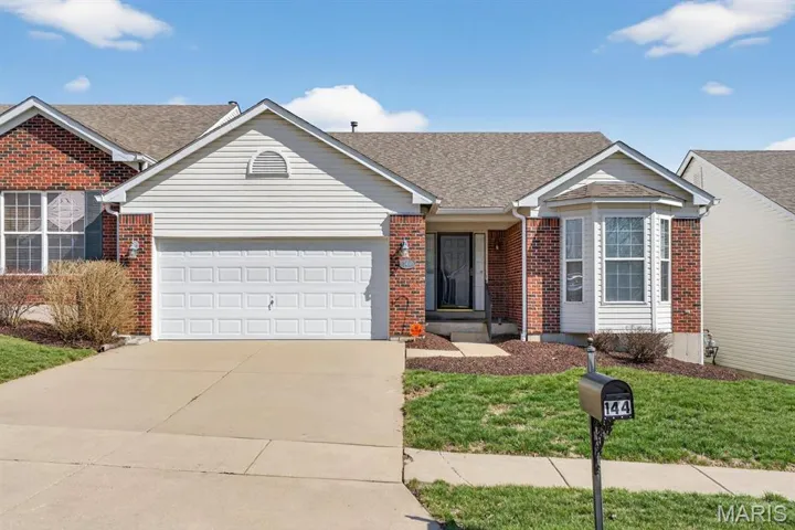 Ranch-style home with brick siding, a garage, concrete driveway, a shingled roof, and a front lawn