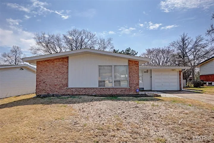 View of front facade featuring an attached garage, brick siding, and driveway