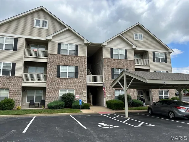 View of property with covered and uncovered parking