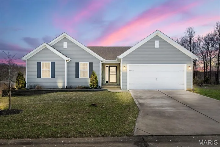 Ranch-style house with concrete driveway, a garage, and a front lawn