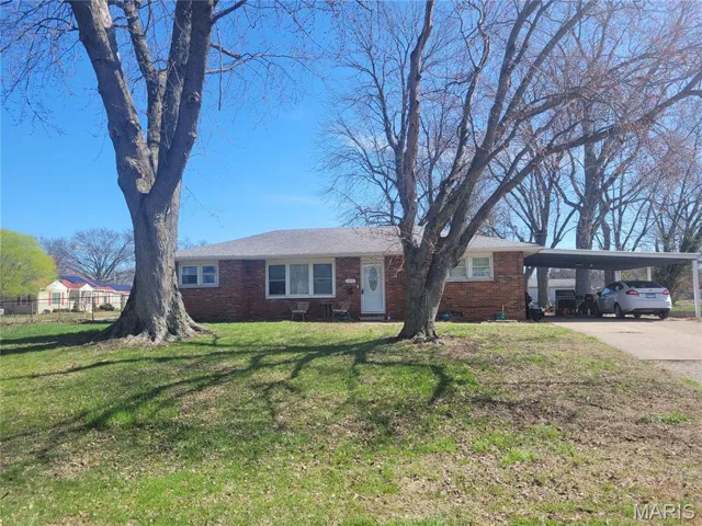 Single story home featuring a carport, brick siding, and driveway