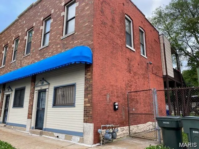 View of side of home featuring brick siding and a gate